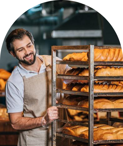 A male baker looks at loaves with a smile